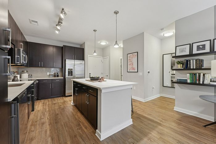Modern kitchen featuring sleek dark cabinetry, a spacious island, and elegant wooden flooring, perfect for culinary enthusiasts.