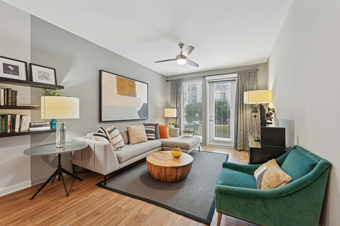 Modern living room featuring a stylish gray sofa, vibrant art piece, and natural light from large windows.