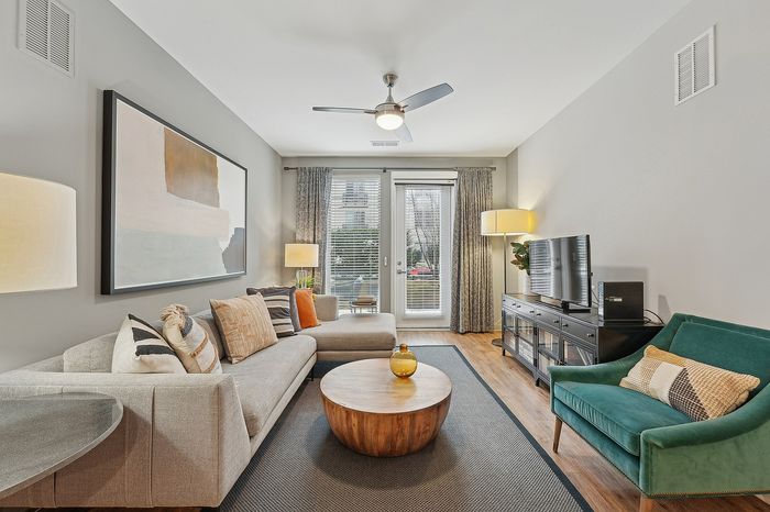 Contemporary living room with stylish decor, featuring a plush L-shaped sofa, vibrant accent chair, and modern art on the wall.