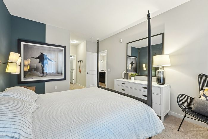 Bright and stylish bedroom featuring a cozy bed, elegant artwork, modern furniture, and ambient lighting for a relaxing atmosphere.