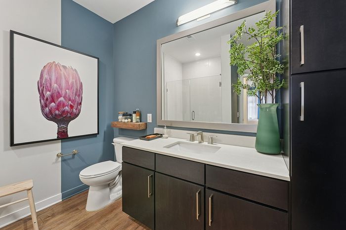 Modern bathroom with sleek fixtures, elegant art piece, and vibrant greenery, creating a serene, stylish sanctuary.