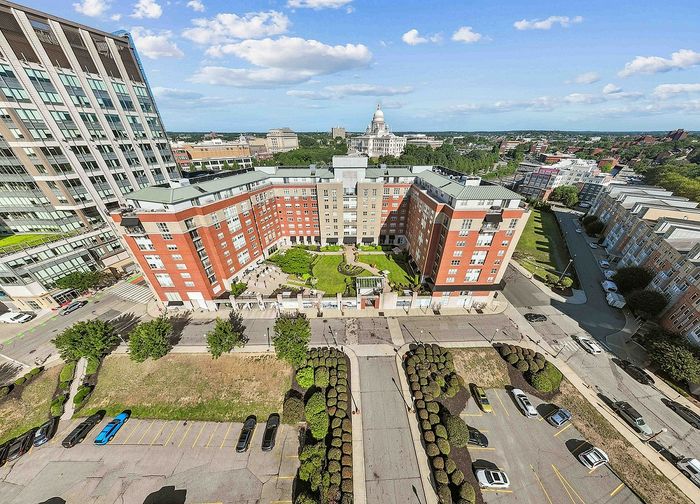 Charming aerial view of a modern apartment complex with a lush central courtyard, located in a vibrant urban area with scenic city views.
