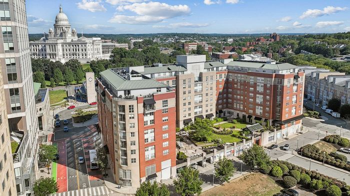Vibrant urban apartment complex with lush green courtyards overlooking a historic landmark, offering a perfect blend of modern living and scenic beauty.