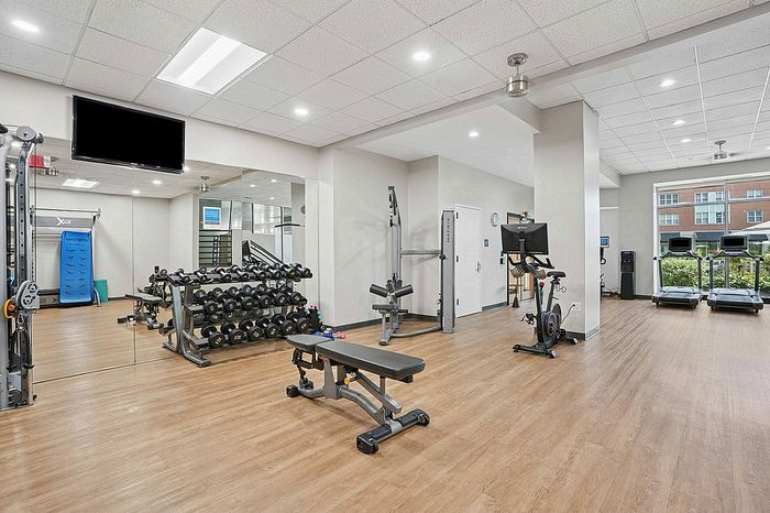 Modern fitness center with state-of-the-art equipment, featuring treadmills, weight racks, and an exercise bike in a spacious, well-lit room.