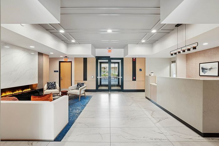 Elegant apartment lobby showcasing modern design with marble floors, cozy seating area, and sleek fireplace.
