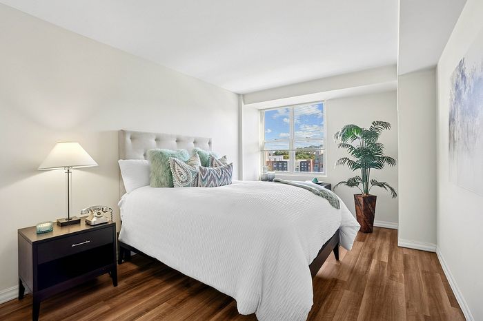 Bright and stylish bedroom with plush bedding, hardwood floors, and large window views.