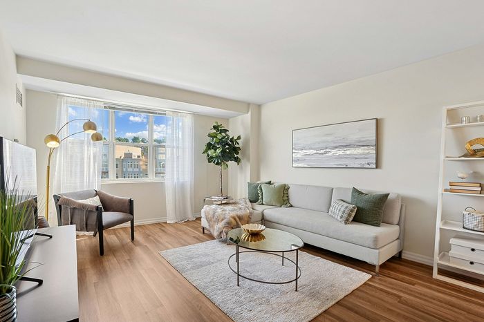 Bright and inviting living room with large window, modern furniture, and stylish decor, perfect for relaxation and entertaining.