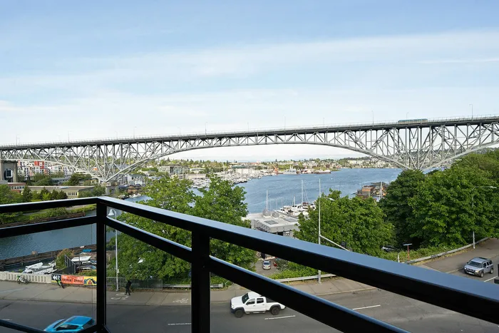 Breathtaking waterfront view of a bustling cityscape with a stunning bridge and lush greenery, perfect for urban living.
