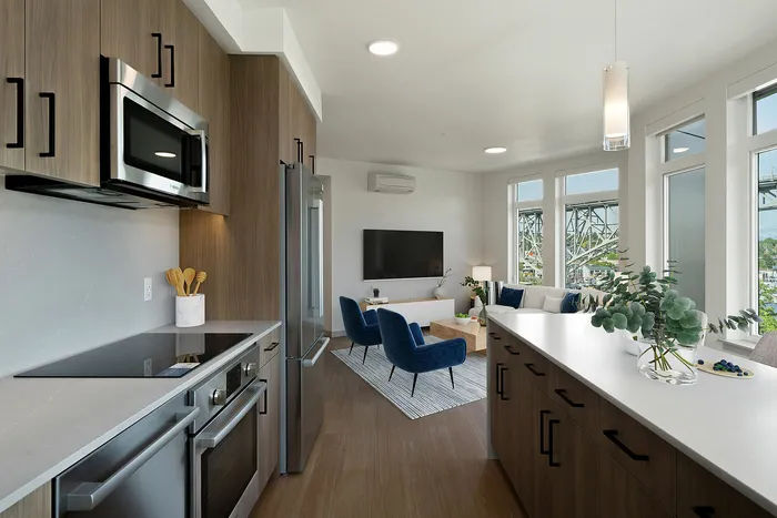 Modern open-concept kitchen and living area with sleek cabinetry, stainless steel appliances, and floor-to-ceiling windows overlooking scenic views.