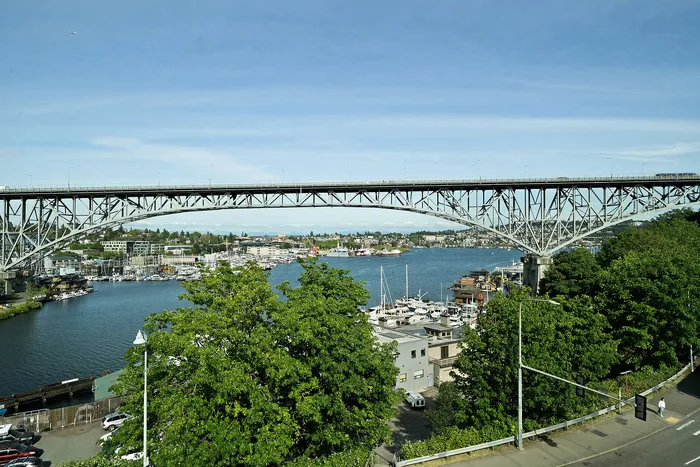Captivating waterfront view with a majestic bridge spanning over a serene body of water, framed by lush greenery and a vibrant marina, perfect for those seeking tranquility and stunning vistas.