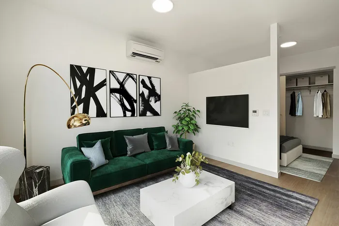 Contemporary living room with chic green velvet sofa, modern art, and spacious walk-in closet in stylish apartment.