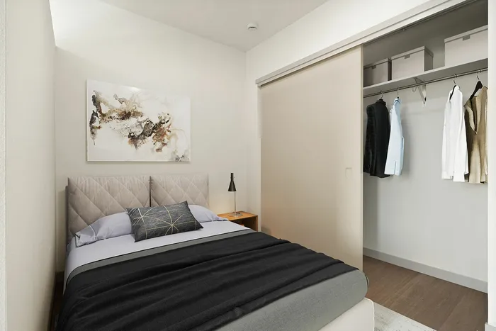 Elegant bedroom with modern decor, featuring a cozy bed, stylish artwork, and a spacious closet with neatly arranged clothing.