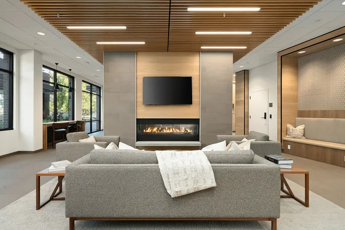 Modern lounge area featuring elegant sofas, a sleek fireplace, and large windows providing natural light.