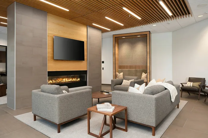 Modern living room with cozy gray sofas, stylish wooden ceiling, a sleek fireplace, and an elegant neutral palette.