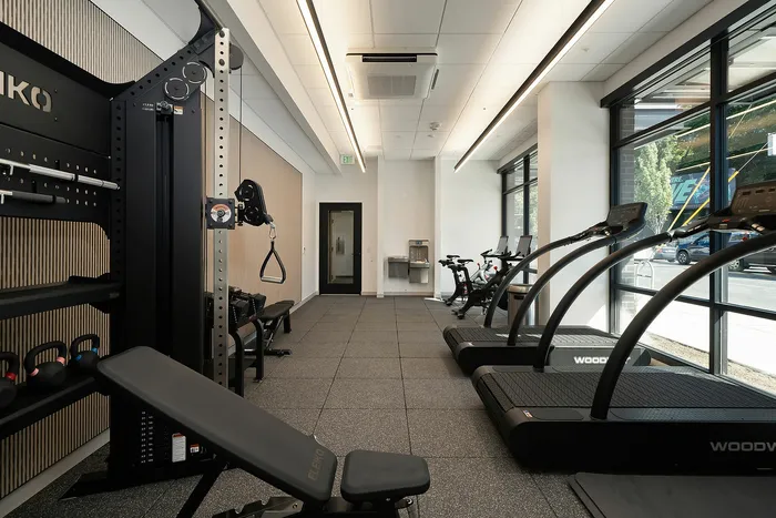Modern apartment fitness center with state-of-the-art treadmills, cycling machines, and versatile strength training equipment.