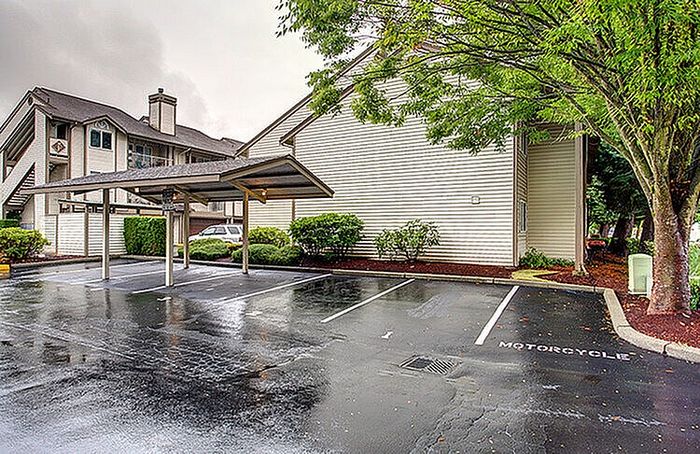 Charming apartment complex with a covered parking area and lush greenery, perfect for a comfortable living experience.