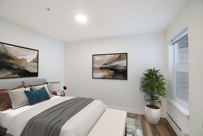 Elegant bedroom with modern artwork, cozy bedding, and natural light streaming through a large window.