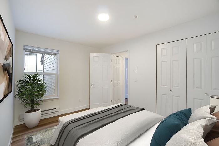 Bright and welcoming bedroom featuring soft neutral tones, a modern plant accent, and ample closet space.