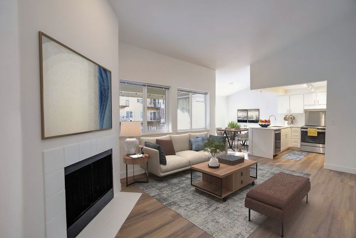 Inviting open-plan living room with stylish decor, cozy fireplace, and modern kitchen in background.