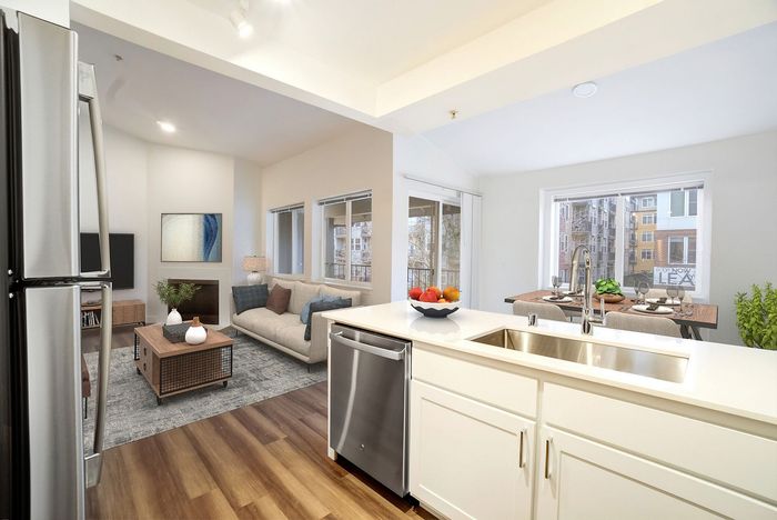 Modern open-plan apartment featuring a sleek kitchen with stainless steel appliances, a cozy living area with natural lighting, and a stylish dining space with large windows.
