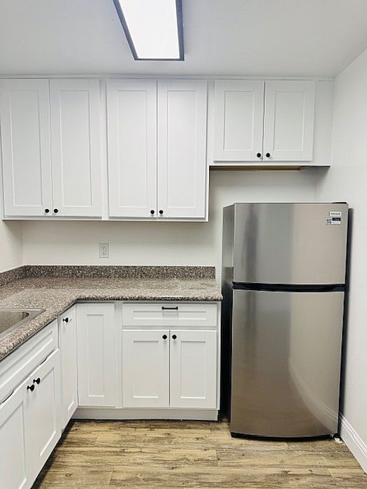 White cabinets, light flooring and stainless steel refrigerator