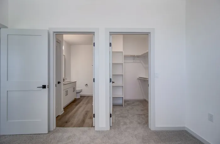 Primary bedroom en suite showing bathroom entrance on the left and walk-in closet with custom shelving on the right at Garrett Forum in Fort Myers, Florida.