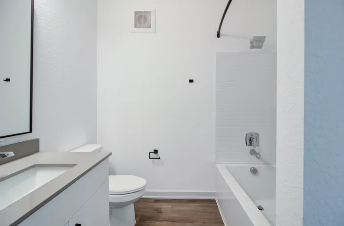 Apartment bathroom with single vanity and sink, shower and tub combo, and spray pattern showerhead at Garrett Forum in Fort Myers, Florida.