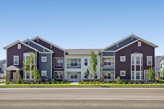 Street-facing exterior view of Garrett Harvest Junction West apartments in Longmont, CO featuring craftsman-style architecture with dark plum and slate blue siding