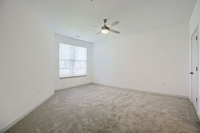 Large carpeted bedroom with window and closet doors at Garrett Harvest Junction West in Longmont, CO
