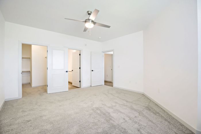 Primary bedroom with walk-in closet and en suite bathroom entry at Garrett Harvest Junction West apartments in Longmont, CO