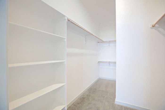 Spacious walk-in closet with built-in shelving and double hanging rods at Garrett Harvest Junction West apartments Longmont CO