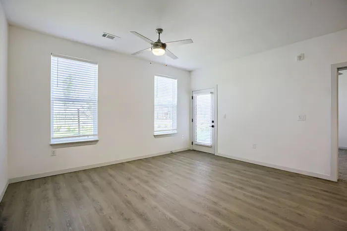 Open living room with luxury vinyl plank flooring, patio door, and large windows at Garrett Harvest Junction West in Longmont, CO