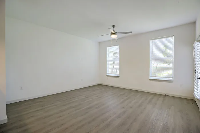Bright living room with luxury vinyl plank floors and two large windows at Garrett Harvest Junction West apartments Longmont CO