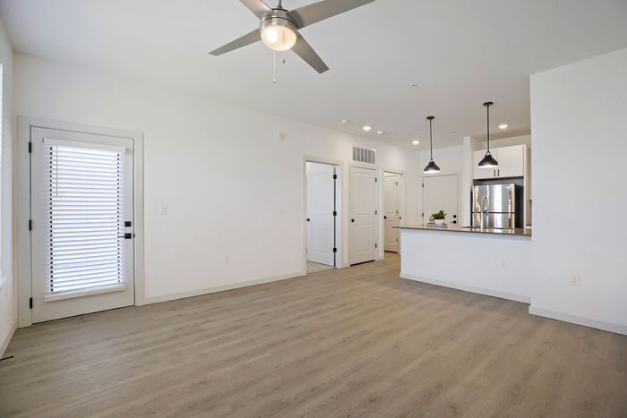 Open concept living room looking toward kitchen with peninsula, pendant lights, and stainless appliances at Garrett Harvest Junction West Longmont CO