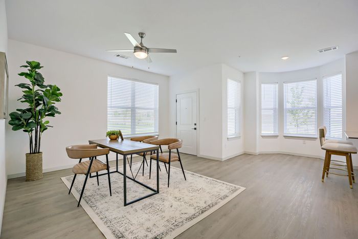 Spacious staged dining room with curved bay window wall, dining table, and open floor plan at Garrett Harvest Junction West Longmont CO