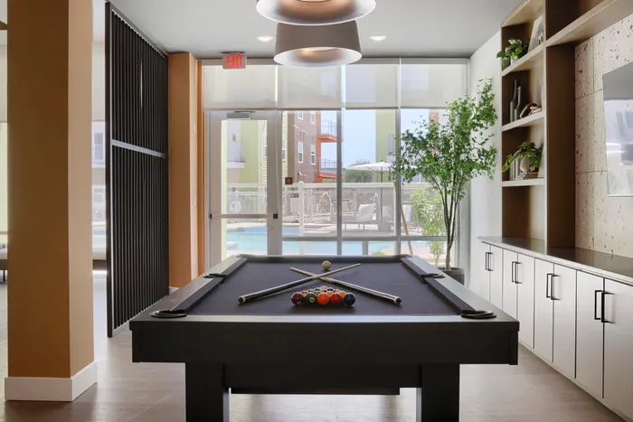 Garrett Uptown clubhouse billiards table with pool courtyard view through floor-to-ceiling windows in Chandler, AZ