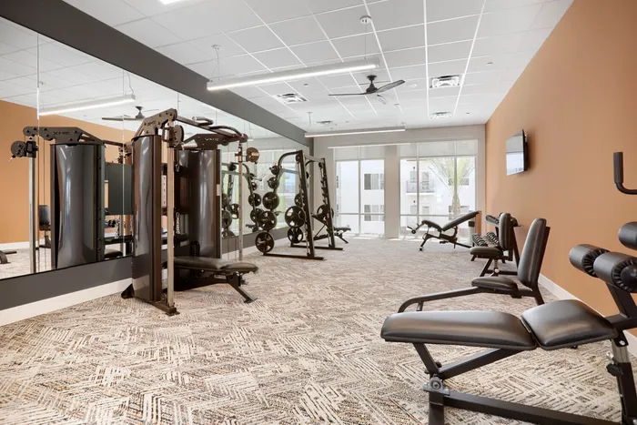 Garrett Uptown fitness center weight room with functional trainer, squat rack, weight benches, and mirrored walls in Chandler, AZ