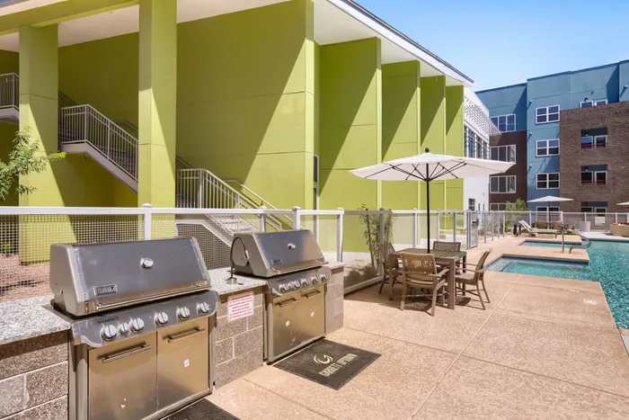 Garrett Uptown poolside outdoor grilling station with two Weber Summit gas grills and dining seating near the pool in Chandler, AZ