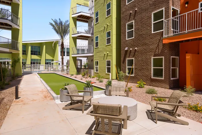 Garrett Uptown outdoor bocce ball court and courtyard lounge seating with desert landscaping and apartment balconies in Chandler, AZ