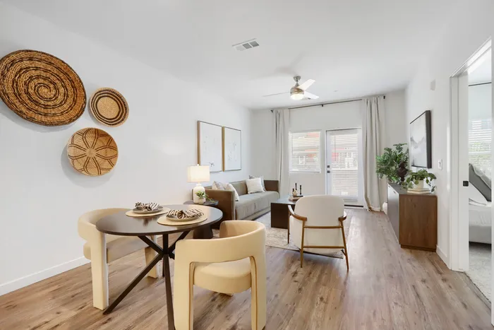 Garrett Uptown B2 apartment open-concept living and dining area with wood-look flooring, patio doors, ceiling fan, and warm natural light in Chandler, AZ