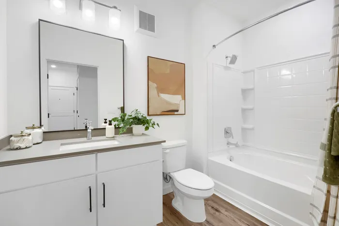 Garrett Uptown B2 apartment secondary bathroom with white vanity, quartz countertop, black-framed mirror, and tub-shower combo in Chandler, AZ