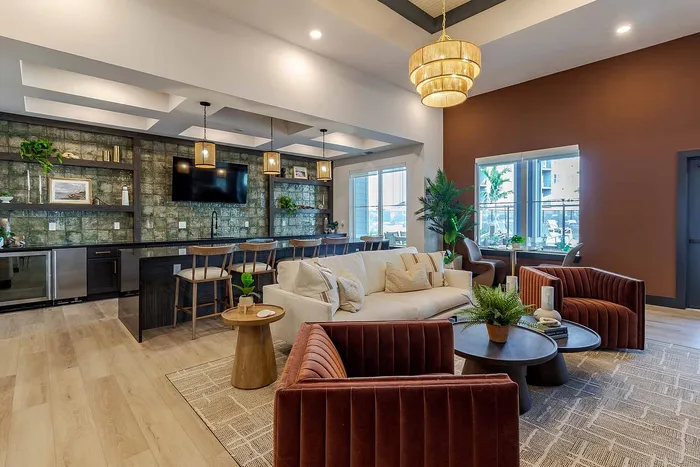 Resident clubhouse lounge with velvet seating, bar stools, and TV at Garrett Gateway apartments in Fort Myers, FL
