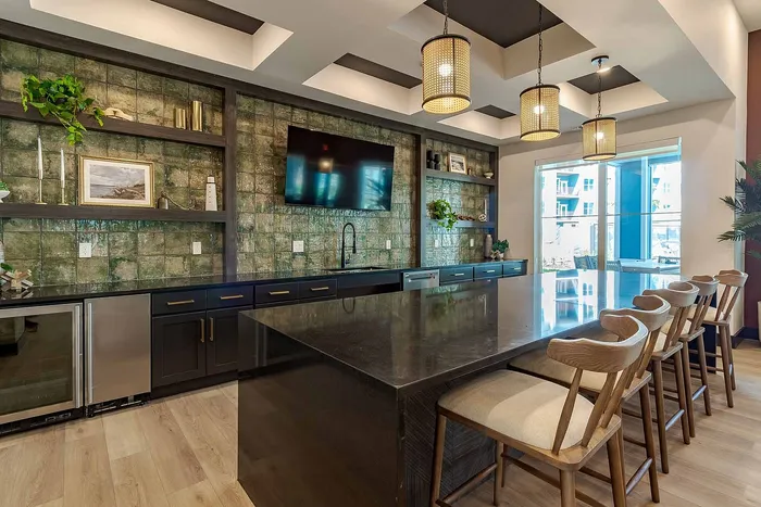 Clubhouse demonstration kitchen with island bar seating and emerald tile backsplash at Garrett Gateway in Fort Myers, FL