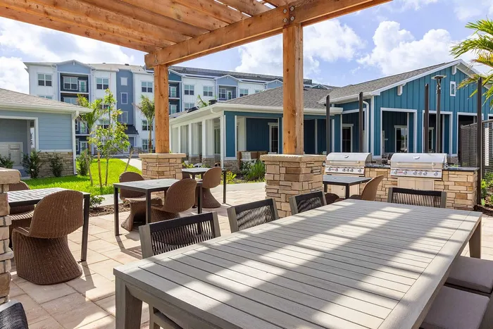 Outdoor patio with gas grills, pergola, and dining tables at Garrett Gateway apartments in Fort Myers, FL
