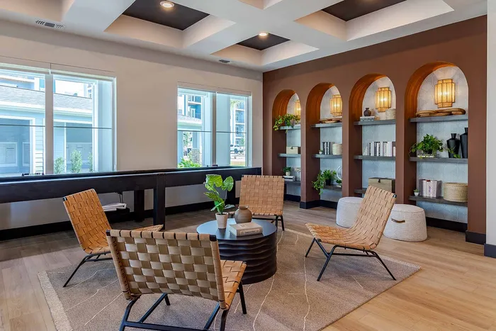 Clubhouse seating area with woven chairs and arched display shelving at Garrett Gateway apartments in Fort Myers, FL