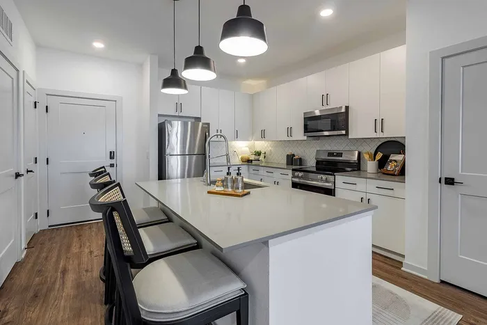 A1 floor plan kitchen with white cabinetry, stainless appliances, and island seating at Garrett Gateway in Fort Myers, FL
