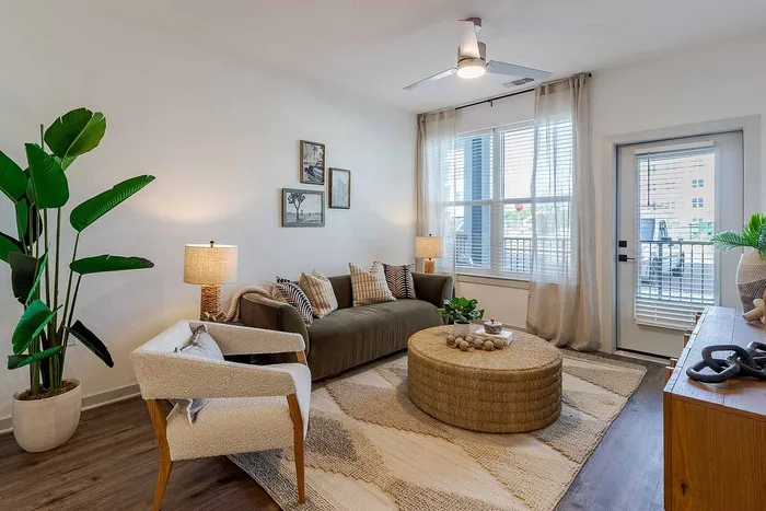 A1 floor plan living room with sofa, large windows, and private balcony access at Garrett Gateway in Fort Myers, FL