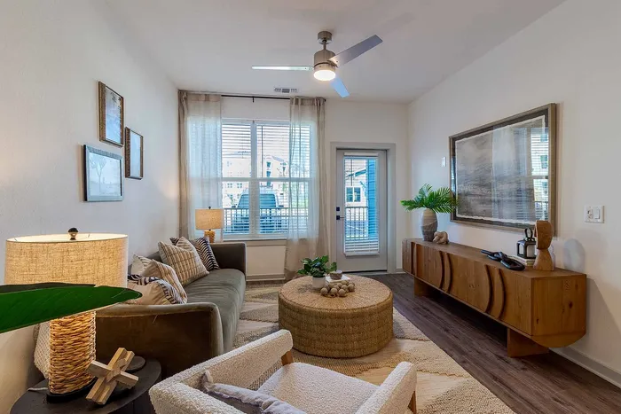 A1 floor plan living room with media console, ceiling fan, and balcony door at Garrett Gateway in Fort Myers, FL