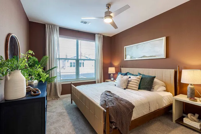 A1 floor plan bedroom with warm accent wall, plush carpet, and large window at Garrett Gateway in Fort Myers, FL