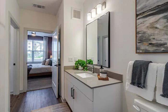 A1 floor plan bathroom vanity with quartz counter, framed mirror, and bedroom view at Garrett Gateway in Fort Myers, FL